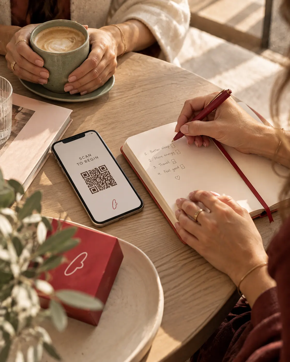 Close-up of hands at a table with an open notebook, a phone and a cup — women sharing their experiences